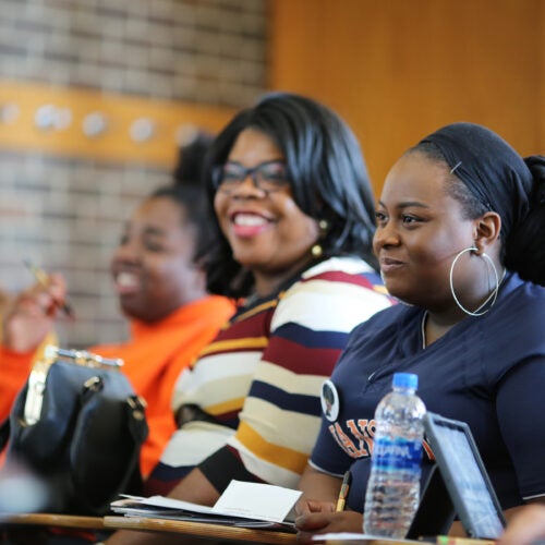 Students in a classroom smiling during a lecture