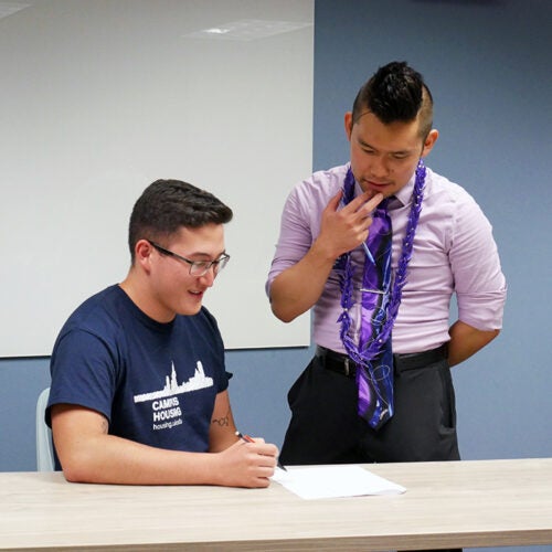 Student sitting with an Honors member standing above them