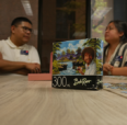 A puzzle box is on a table with advisors in the background