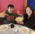 Students smiling and pointing at a some dumplings