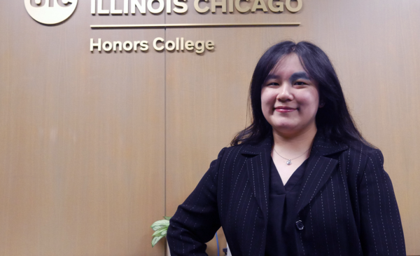 Student standing in front of UIC Honors College logo
